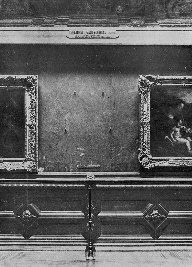 An old photograph of a museum wall with four metal hooks where a painting used to hang
