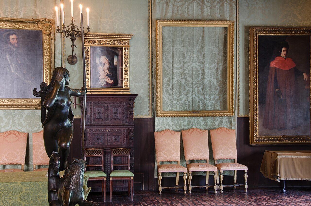 Empty gilded picture frames hanging on a richly decorated museum wall